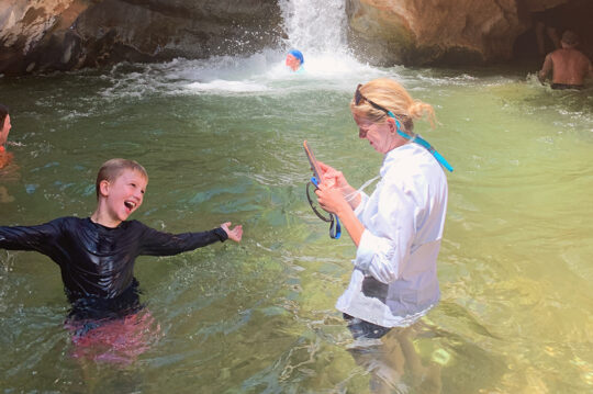 Mom using a cell phone to take a photo of her son