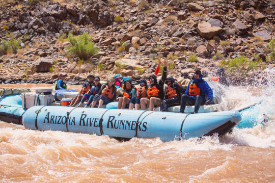 People smiling on a raft after a rapid