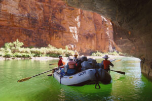 An oar boat floats in emerald green water. 