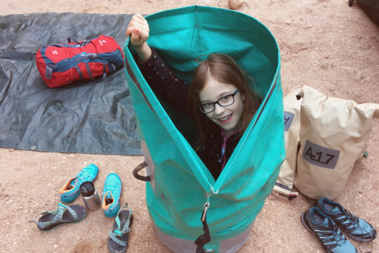 A child playfully is seen in a large dry bag.