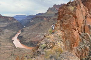 A person hiking high above the Colorado River on a ridge.