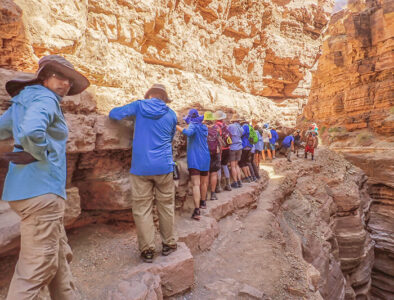 Hikers hiking on steep ledge.