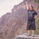 A girl with downs syndrome holding her hand in the air smiling