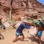 A man carrying a woman next to a waterfall