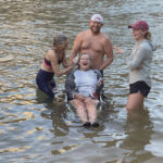 A person in a wheel chair getting her hair washed in the Colorado River.