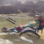 A person in a wheel chair taking a nap while in the Colorado River.