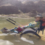 A person in a wheel chair taking a nap while in the Colorado River.