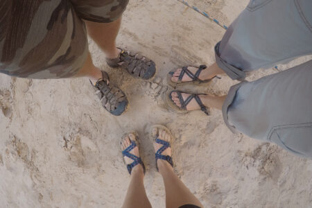 Three people with different types of river sandals.