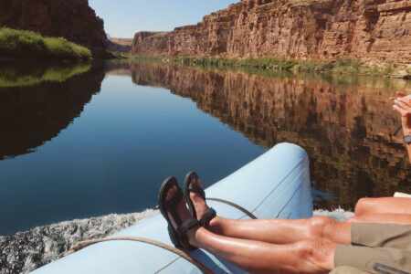 A person with their feet up on a motor boat in the Grand Canyon.