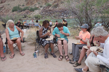 A group of people sitting in chairs eating food in the Grand Canyon.