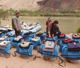 Guides arrange dry bags on a beach in Grand Canyon.