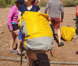 A woman carrying a large dry bag.